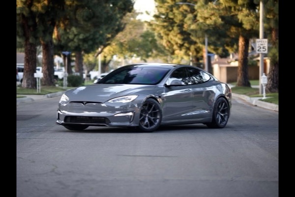 Gray Tesla Model S sedan on a residential street at golden hour